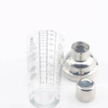 The Glass Cocktail Shaker with Classic Recipes and Measurements on the side. The strainer and cap sitting next to it.