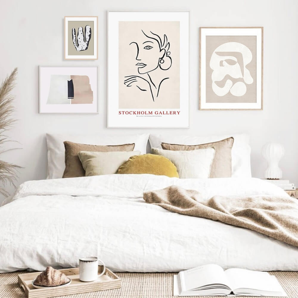 4 modern abstract Scandinavian art painting posters in an bedroom hanging on the wall behind a bed